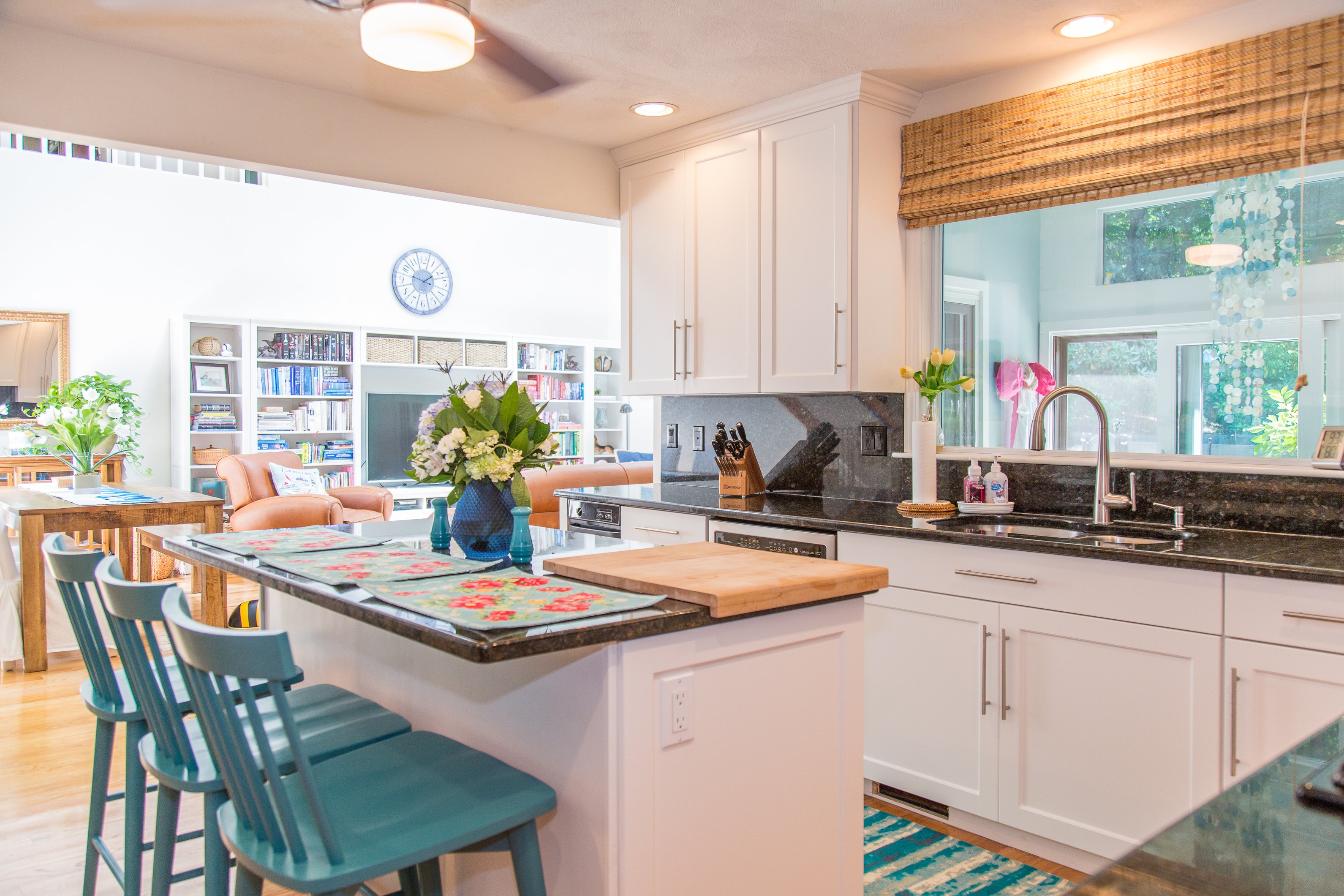 White Cabinetry with a black countertop and backsplash and light wood flooring