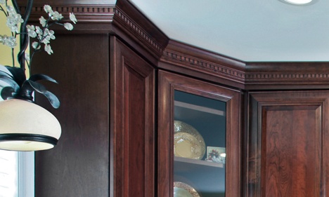 Dark Wood Glass-Front Kitchen Cabinet with Dentil Crown Molding