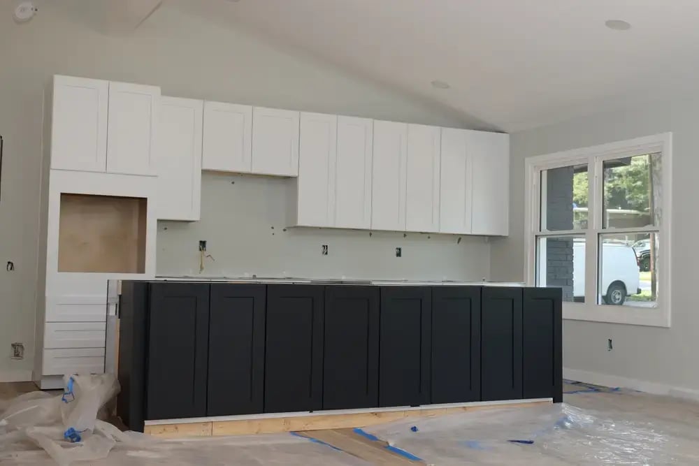 modern kitchen under construction with two-tone cabinets and unfinished remodeling work