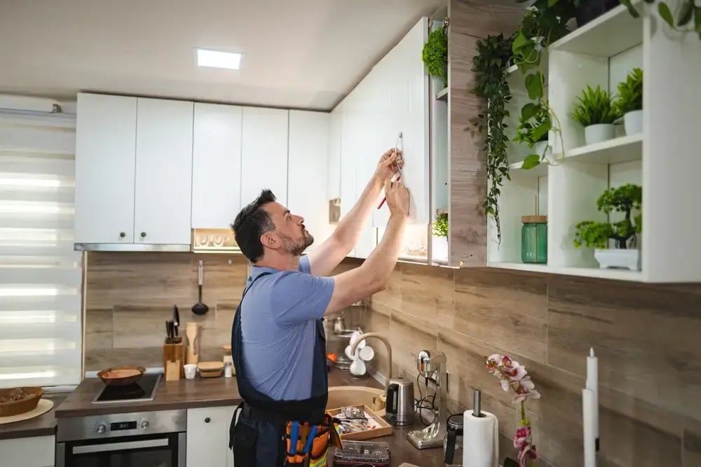 installer fitting new kitchen cabinets in a modern apartment remodel